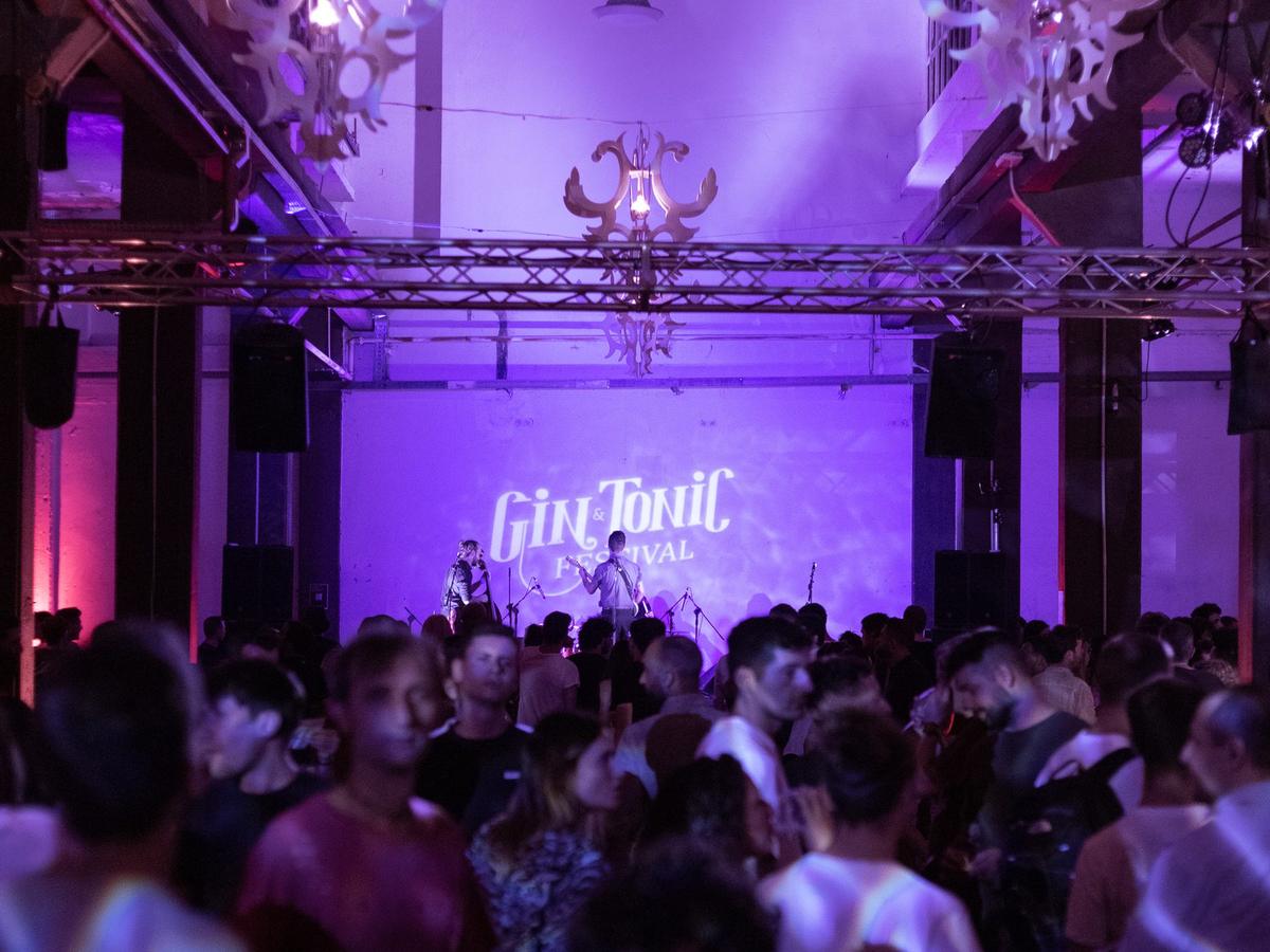 Pubblico che balla sotto luci viola con il logo del festival proiettato